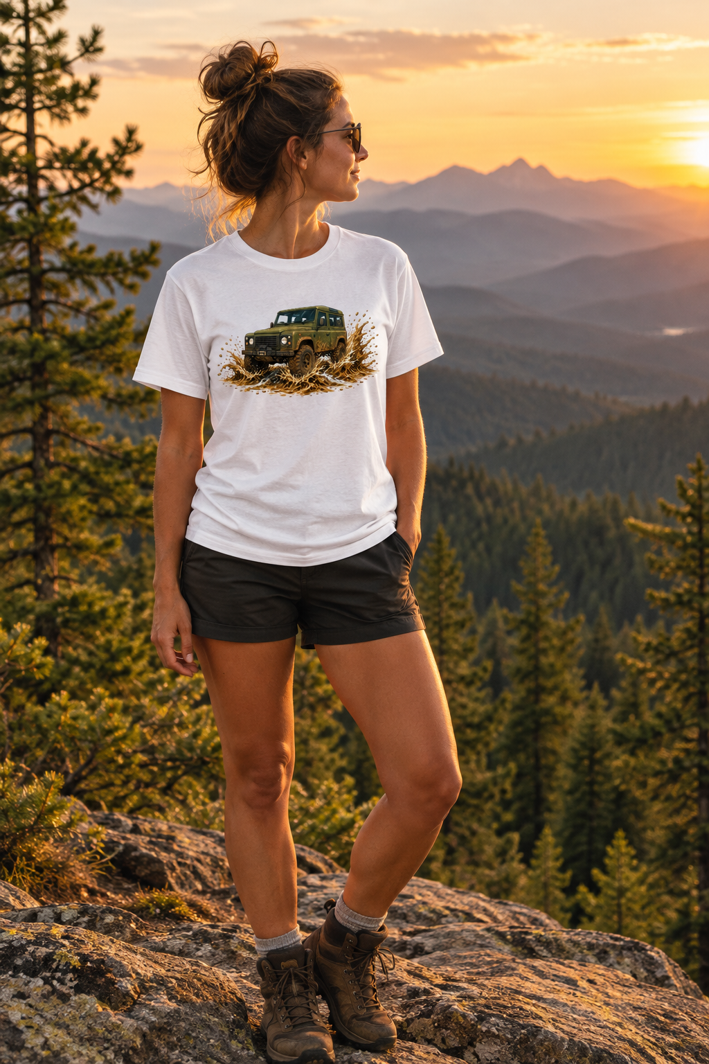 Woman on a rocky overlook with mountain landscape wearing the tee